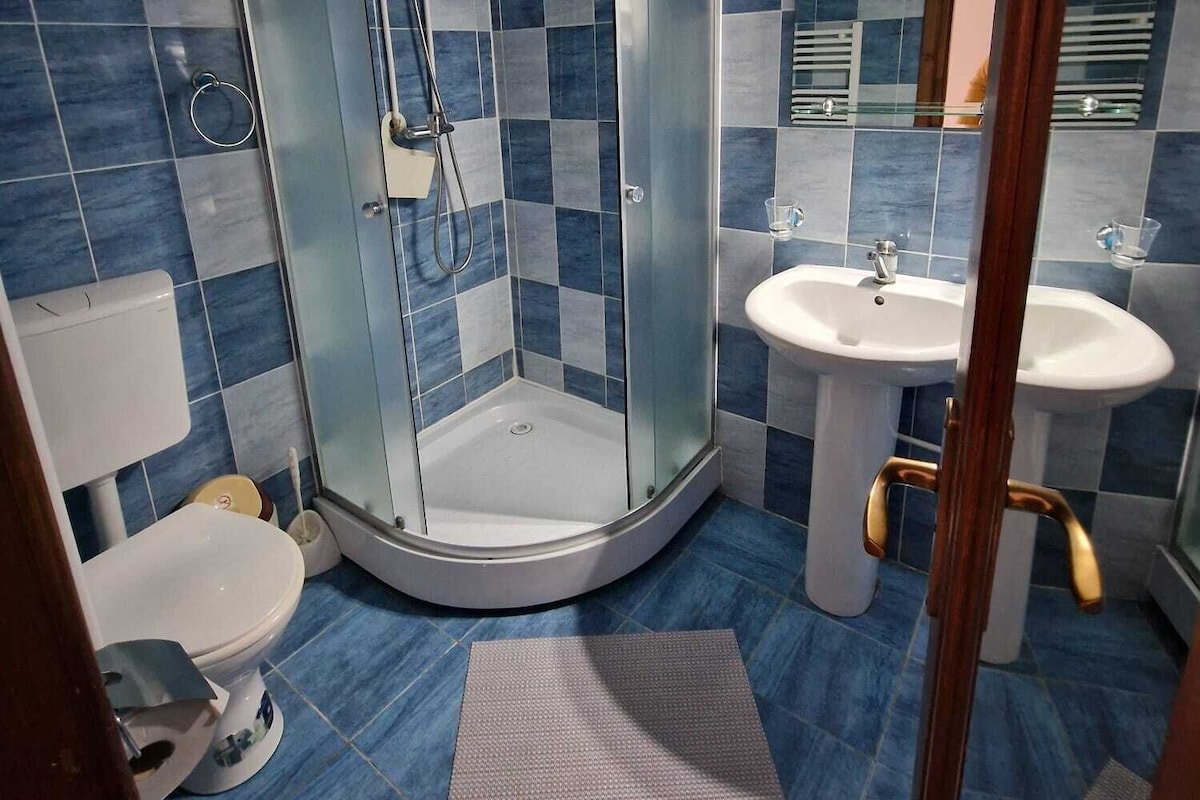 Un baño con ducha envuelta en vidrio, inodoro, lavamanos y espejo.