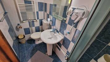A bathroom with a white sink, a toilet, a glass shower enclosure, and a mirror.