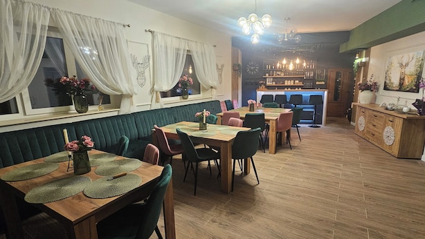 A dining area with a wooden table, chairs, and a green upholstered bench. - Villa Ileana  (Ceahlău)