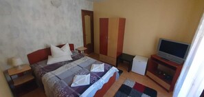 A bedroom with a bed, a wardrobe, a television, and a small table.