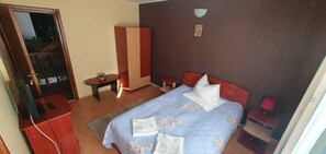 A bedroom with a bed, bedside tables, a wardrobe, and a small table with a lamp. - Villa Ileana (Ceahlău)