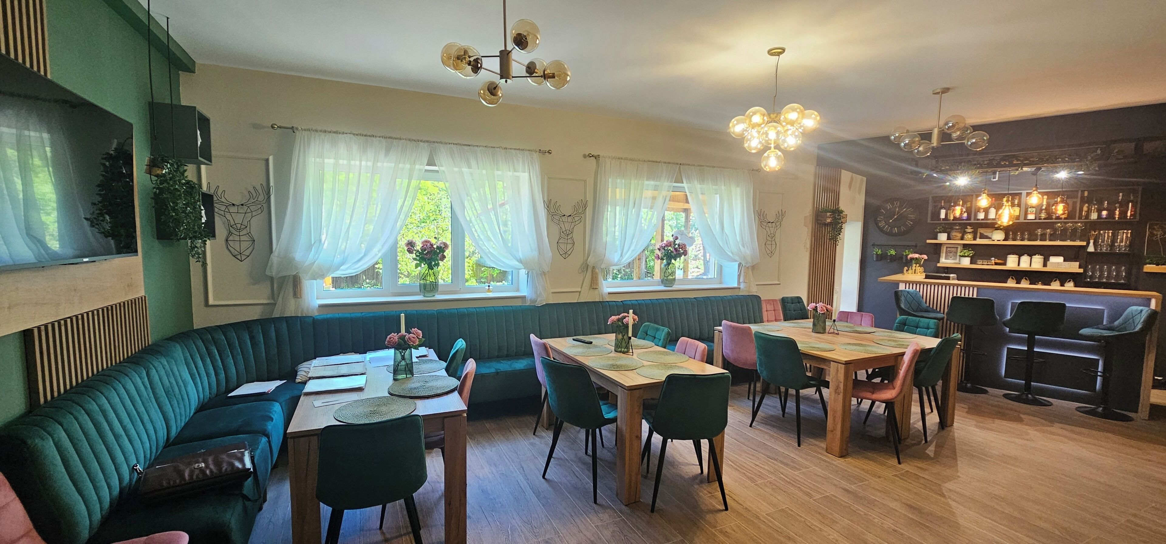 A cozy dining area with a green upholstered bench, wooden tables, and chairs.