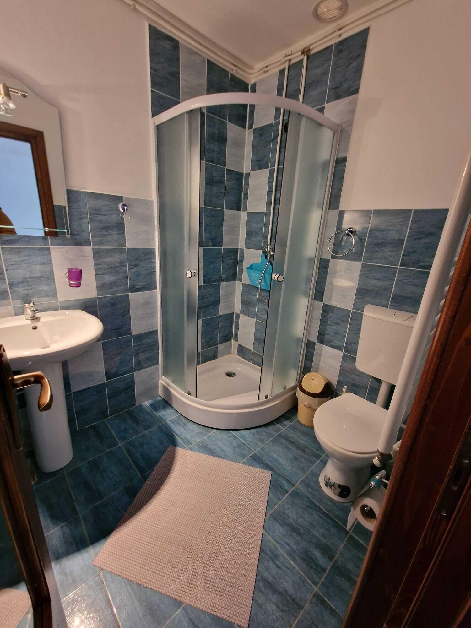 Un baño con cabina de ducha de vidrio, lavamanos e inodoro.