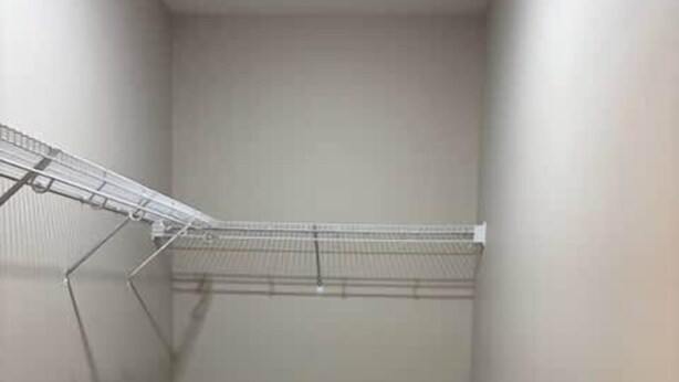 A small, enclosed closet with a metal drying rack and a carpeted floor.