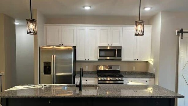 A modern kitchen with a central island, stainless steel appliances, and pendant lighting. - 3bed 2 bath with King master Sycamore (Sycamore)