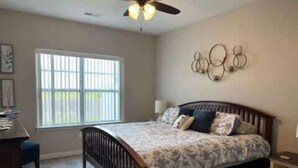 A bedroom with a bed, a desk, a chair, a window, and a ceiling fan. - 3bed 2 bath with King master Sycamore (Sycamore)