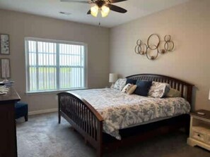 A bedroom with a bed, a desk, a chair, a window, and a ceiling fan. - 3bed 2 bath with King master Sycamore (Sycamore)