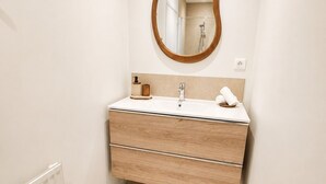 Un bany amb un lavabo de fusta, un mirall rodó, una tovallola i una catifa blanca.