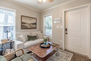 A living room with a sofa, a coffee table, a lamp, and a painting on the wall. - Coastal charm awaits in this cozy 1-bed, 1-bath home on Fairhope’s Scenic Hwy 98 (Fairhope)