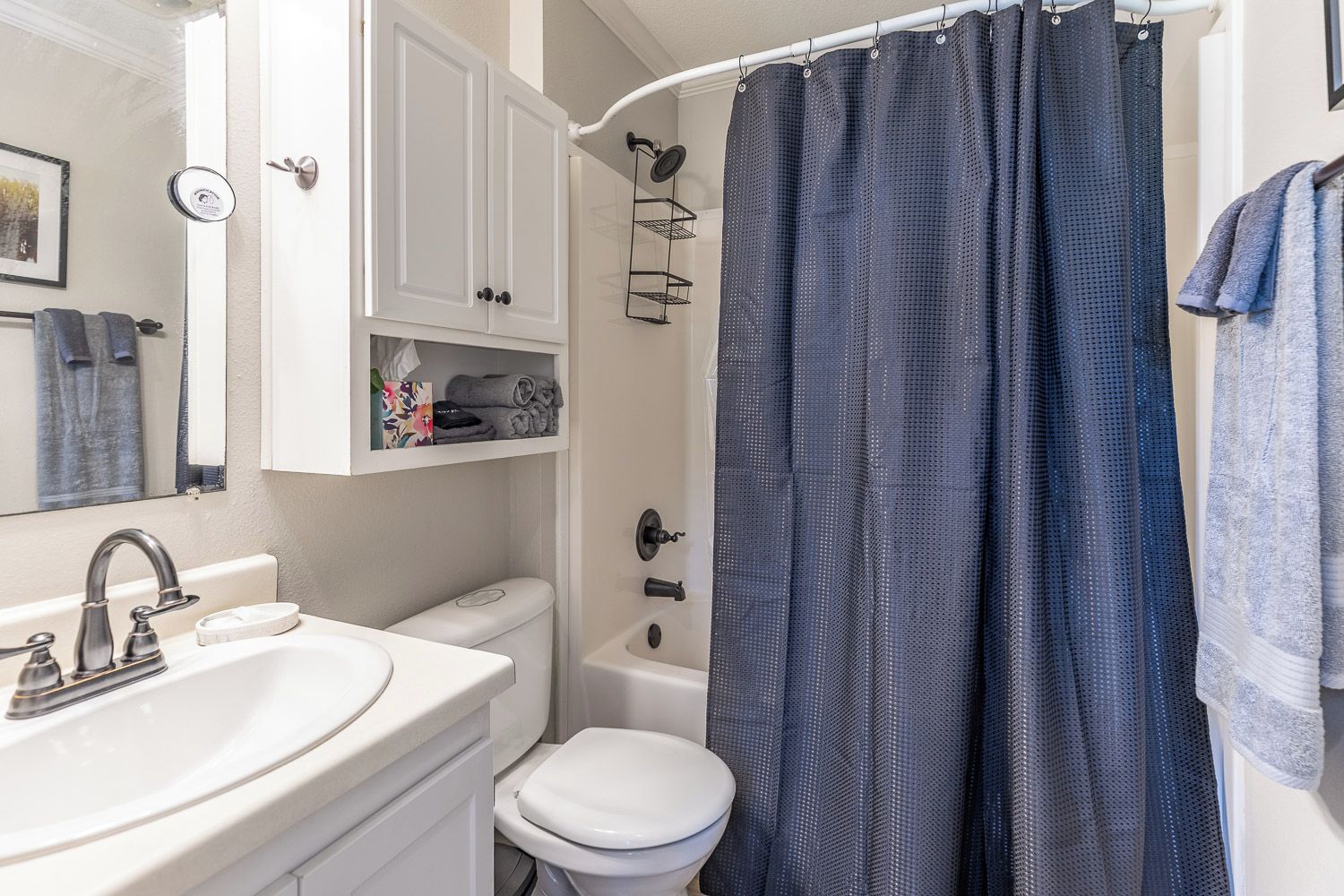 A bathroom with a white sink, toilet, and shower curtain.