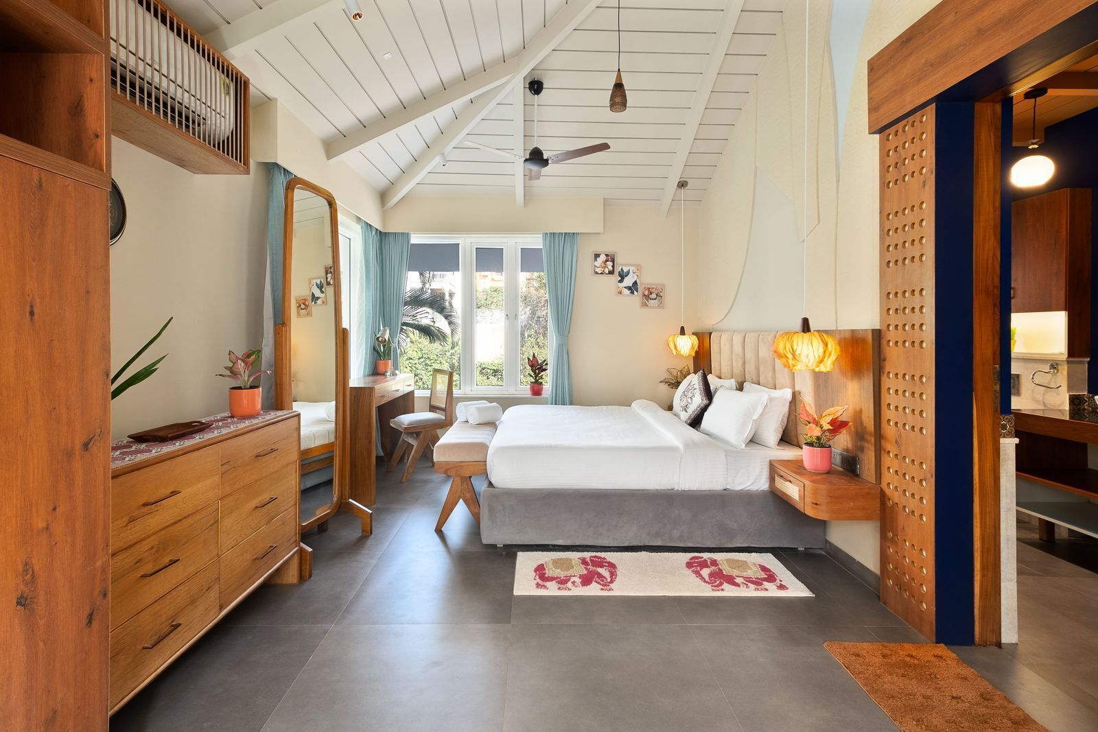 Ein Schlafzimmer mit einem Bett, Nachttischen, einem Schreibtisch, einem Stuhl, einem Kleiderschrank, einem Spiegel und einem Deckenventilator.