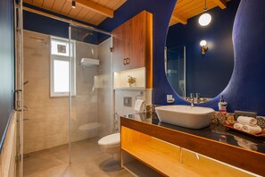 Ein modernes Badezimmer mit einer Duschkabine aus Glas, einem Holzlagerraum und einem großen Spiegel.