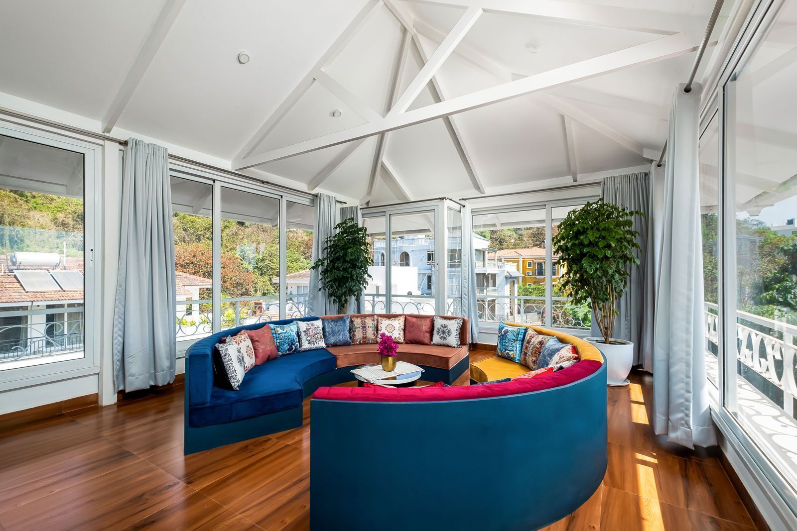 Ein modernes Wohnzimmer mit einer gebogenen, blauen Couch, einem Couchtisch und zwei Kübelpflanzen.