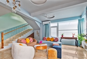 A spacious living area with a staircase, a ceiling fan, and a view of the outdoors.