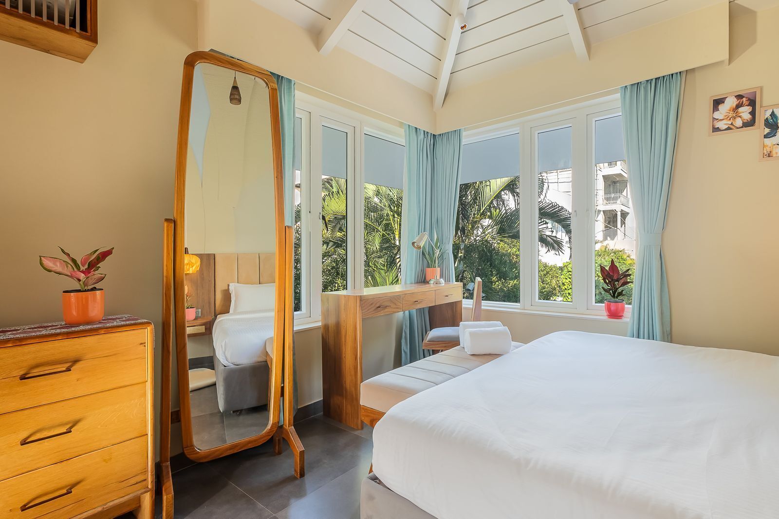 Ein Schlafzimmer mit einem Bett, einem Schminktisch, einem Schreibtisch und einem Fenster mit Vorhängen.