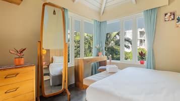 Ein Schlafzimmer mit einem Bett, einem Schminktisch, einem Schreibtisch und einem Fenster mit Vorhängen.