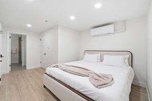 Quarto com cama, porta e ar condicionado.