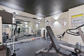 Une salle de sport équipée de divers appareils d’exercice, d’un miroir et de panneaux explicatifs accrochés au mur.