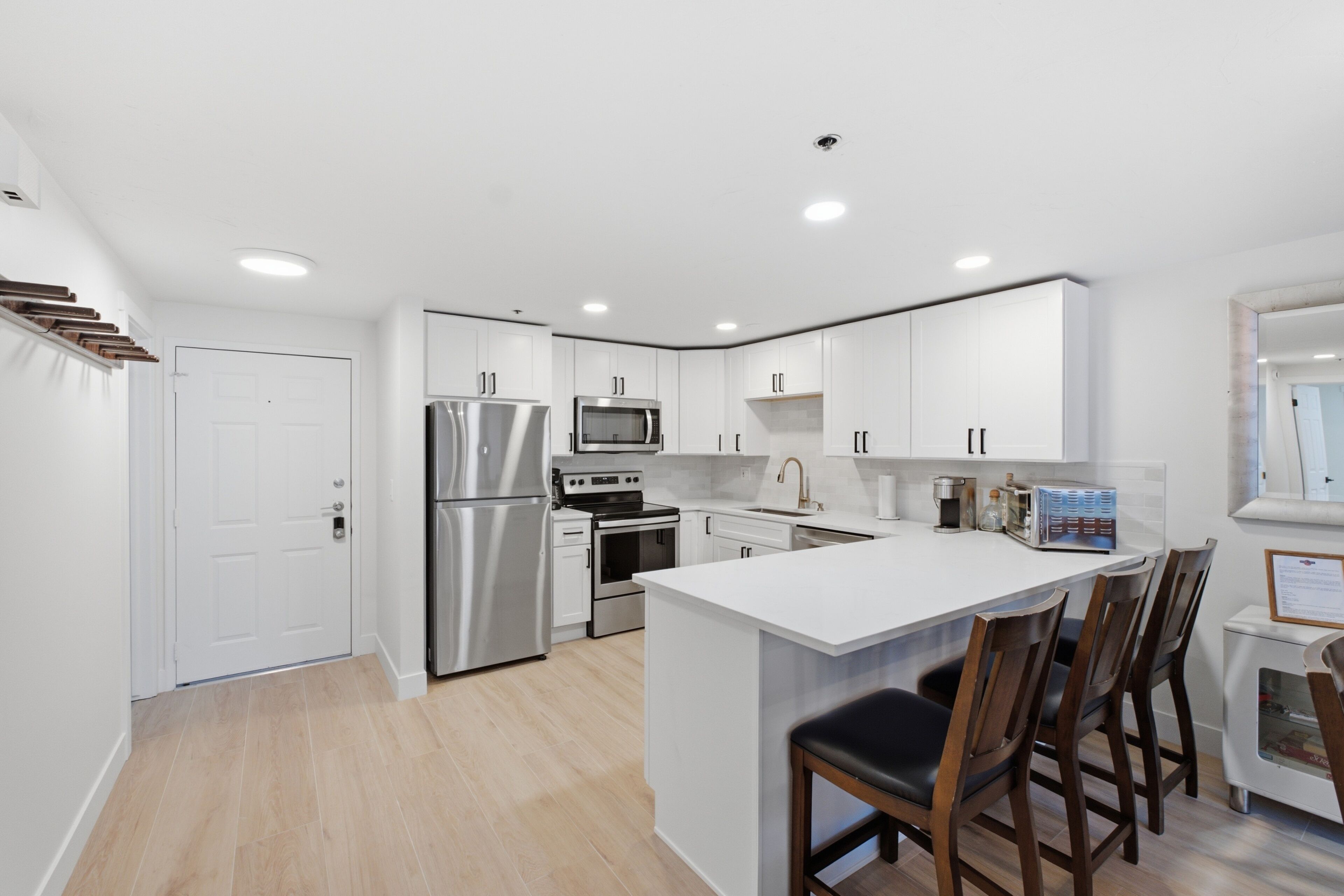 A modern kitchen with white cabinetry, stainless steel appliances, and a central island with bar stools.