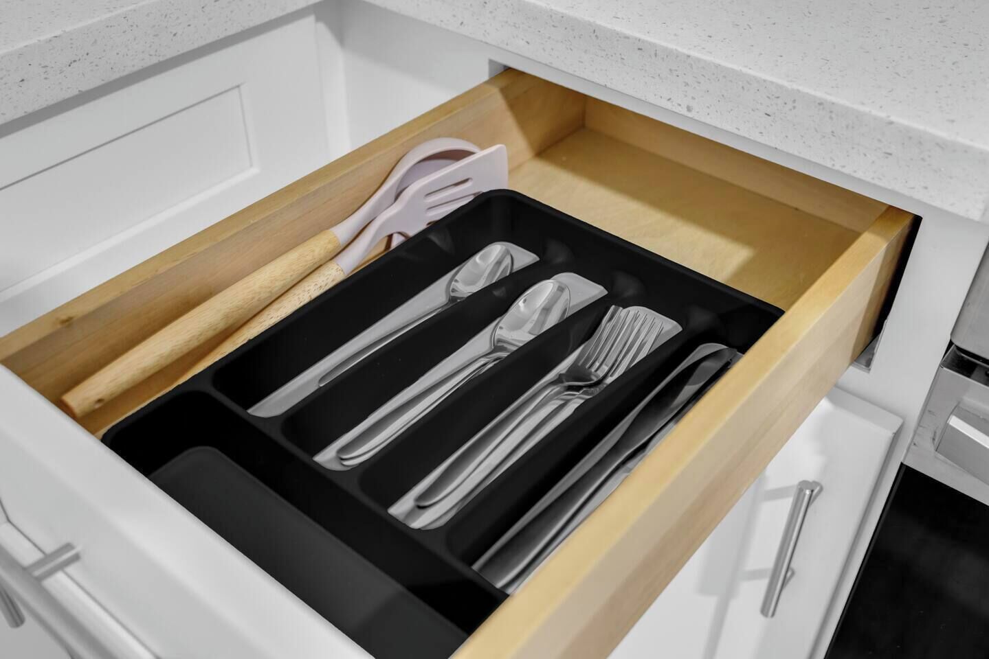 A drawer with utensils including a fork, knife, and spoon.