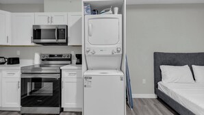 Cocina compacta equipada con microondas, estufa, horno y lavadora blanca.