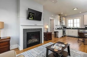 Una sala de estar moderna con chimenea, un televisor montado arriba y un comedor con mesa y sillas.