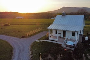 Una casa de un piso con porche, jacuzzi y vistas a un campo y montañas.