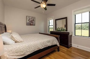 Un dormitorio con cama, ventilador de techo, cómoda y ventana con vistas.