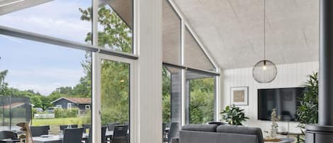 A spacious living area with large windows, a modern fireplace, and a dining area with outdoor seating.
