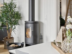 A modern kitchen with a wood-burning stove, a dining table, and a potted plant. - 16 Person Holiday Home in Albaek (Aalbaek)