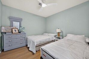 A bedroom with two beds, a dresser, a mirror, a ceiling fan, and a nightstand with a lamp. - Spacious 4-bedroom house in charming Mary Esther (Mary Esther)