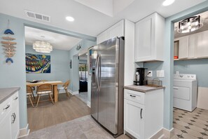 A modern kitchen with a stainless steel refrigerator, white cabinetry, and a dining area with a wooden table and chairs. - Spacious 4-bedroom house in charming Mary Esther (Mary Esther)