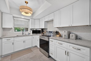 Een moderne keuken met witte kasten, roestvrijstalen apparatuur en een ingebouwde oven.