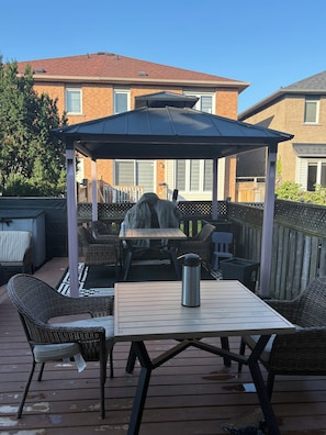 A patio area with a table, chairs, a covered seating area, and a metal water bottle.