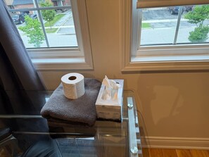 A bathroom with a window, a towel, a toilet paper roll, and a tissue box. - Beautiful 5 Bedroom Home In Heartland near YYZ , Attractions and more !!! (Mississauga)
