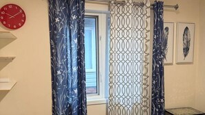 Un dormitorio con cama, cortinas, un reloj y una ventana.