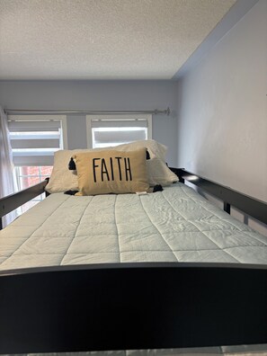 A bed with a quilted mattress and a pillow with the word 'FAITH' on it. - Beautiful 5 Bedroom Home In Heartland near YYZ , Attractions and more !!! (Mississauga)