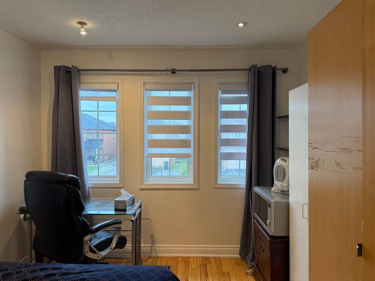 A small room with a desk, chair, and a window with blinds.