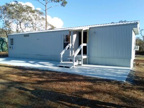 A single-story mobile home with a front porch and a staircase leading to the entrance. - Keaton Beach Lodge, serene, private parking for several towing vehicles & boats (Perry)