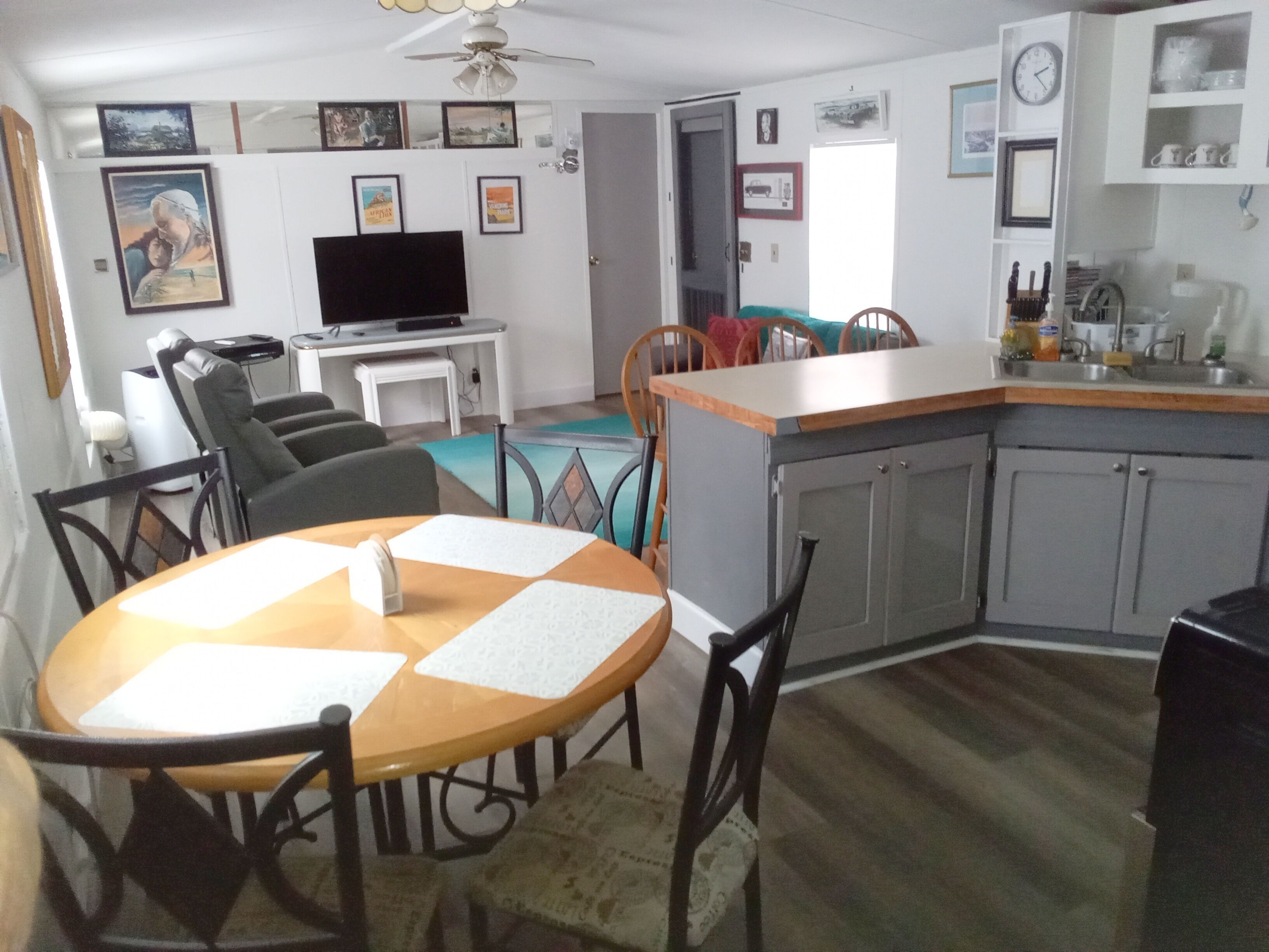 A dining area with a round table, chairs, and a kitchen in the background.