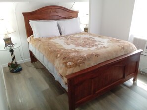 A wooden bed with a headboard, white pillows, and a patterned bedspread in a room with a wooden floor. - Keaton Beach Lodge, serene, private parking for several towing vehicles & boats (Perry)