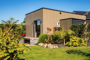 Een modern gebouw met een plat dak, een ruime open entree en een verzorgde tuin met diverse planten en een pad van natuursteen.