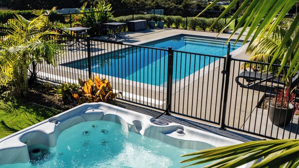 Piscina com hidromassagem, cercada por uma grade, e vista para uma paisagem montanhosa.