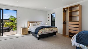 Quarto com cama, mesa de cabeceira, armário e vista para o exterior.