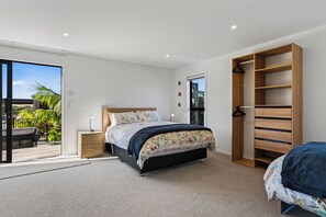 Een slaapkamer met een bed, nachtkastje, hangkast en uitzicht op de omgeving.