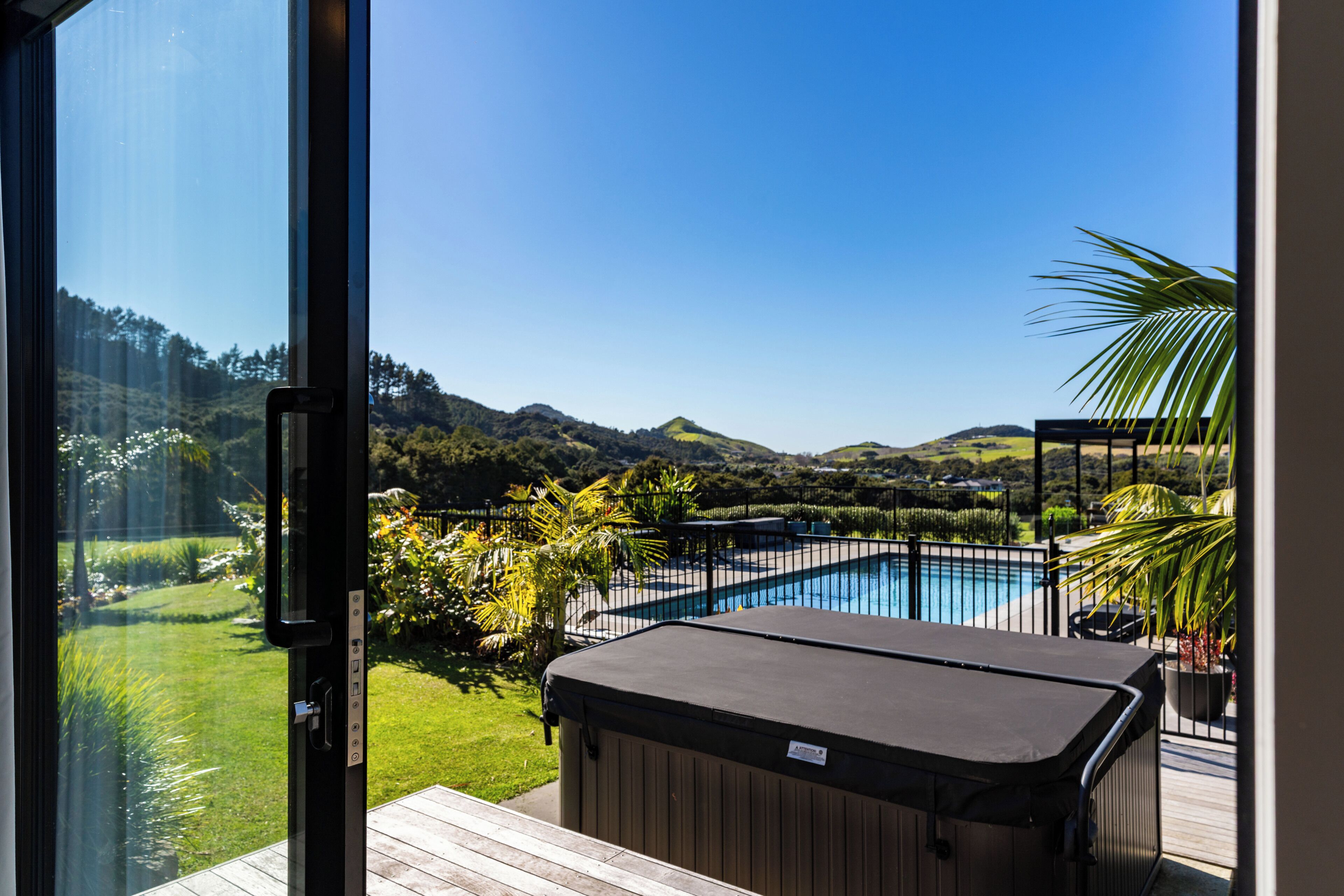 A pool area with a hot tub, surrounded by a wooden deck and a view of a mountain landscape.