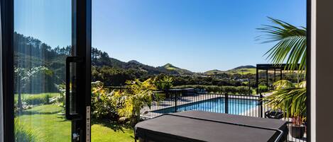 A pool area with a hot tub, surrounded by a wooden deck and a view of a mountain landscape.