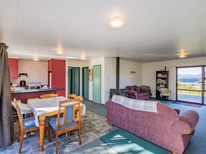 Ein gemütlicher Wohnbereich mit einer Couch, einem Esstisch mit Stühlen, einer Küchenzeile und einem Balkon mit Blick.