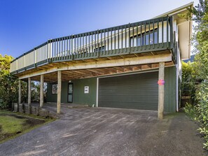 Ein Gebäude mit einer überdachten Veranda, einer Garage und einer Tür mit einem Schild.