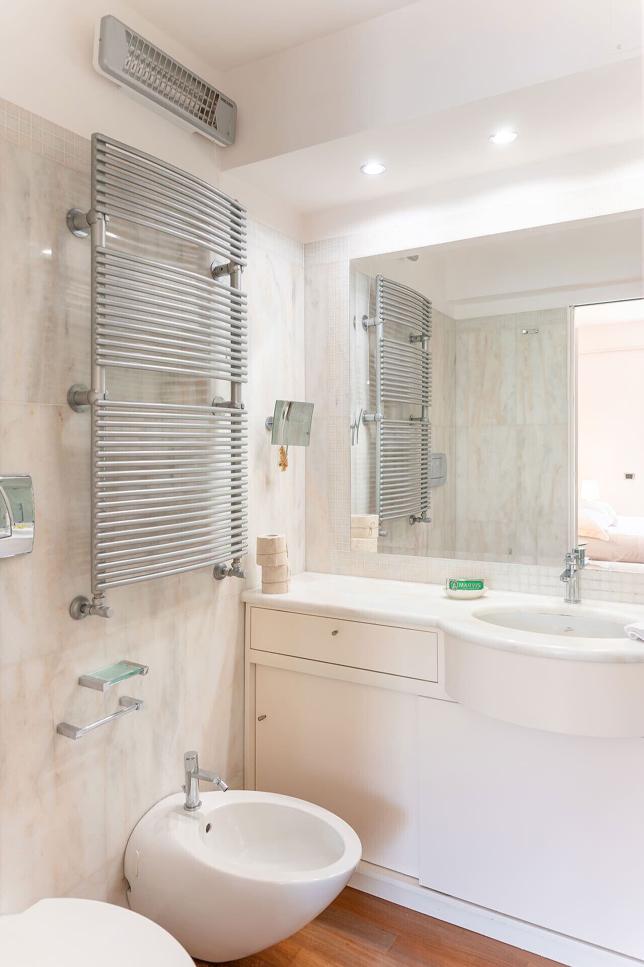 A modern bathroom with a large mirror, a white sink, and a bidet.